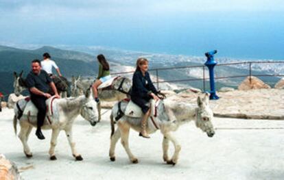 Los turistas disfrutan de un paseo en burro en lo alto del monte Calamorro de Benalmádena.