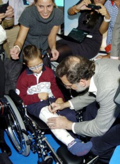 Mariano Rajoy firma en la escayola de un niño durante el mitin ofrecido por esta formación en Badajoz.
