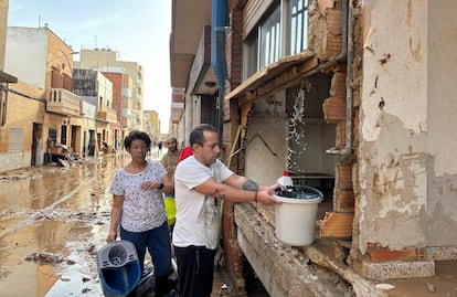 Vecinos de Massanassa recogen agua de una tubera rota en una calle de la localidad, este jueves. 