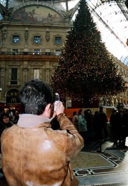 Un hombre fotografía con su móvil un árbol de Navidad en Milán.