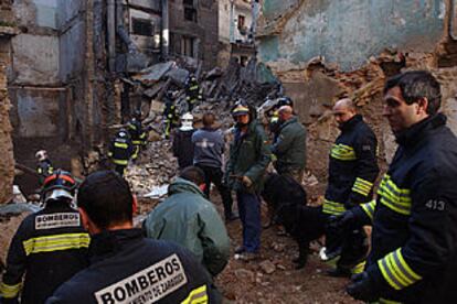 Los bomberos, entre los restos del edificio derrumbado.