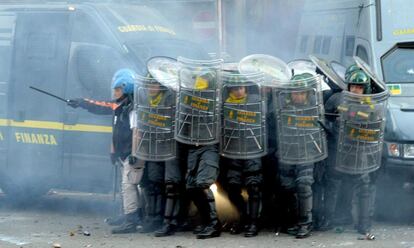 Los policías se protegen del lanzamiento de objetos de los manifestantes.