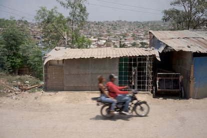 Una moto pasa por delante de una vivienda precaria en el barrio Cerros de Albornoz.