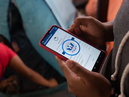 Una migrante mira en su teléfono móvil la aplicación CBP One en el albergue Juventud 2000, en Tijuana.