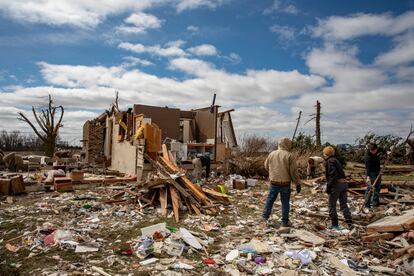 Family and neighbors look through debris on Ed Whestine's farm southwest of Wellman, Iowa on Saturday