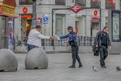 Un policía municipal de Madrid pone una multa a un viandante por no respetar la cuarentena en Madrid.