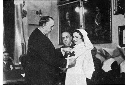 El que fuera presidente de Cruz Roja en 1936, Ángel Guirao, coloca un brazalete a una nueva "dama enfermera".