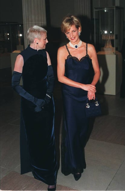 El viaje que realizó Diana de Gales en 1996 a Nueva York (Estados Unidos) dio mucho que hablar por sus estilismos. En la imagen, Lady Di lució un vestido lencera azul marino, con una gargantilla de perlas, en la gala del Instituto de la Moda del Metropolitan Museum de Nueva York. La acompaña la actriz Liz Tilberis.