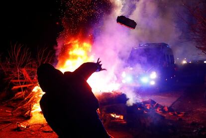 Un manifestante tira una piedra a un furgón policial, durante los disturbios en Ucrania por la llegada de 72 evacuados de la ciudad china de Wuhan.