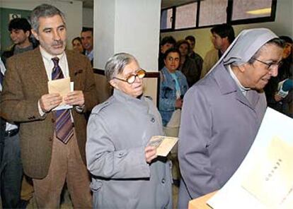 El candidato de Izquierda Unida a la Presidencia del Gobierno, Gaspar Llamazares, espera detrás de un grupo de monjas para depositar su voto en el madrileño Instituto Joaquín Turina.