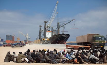 Un grupo de emigrantes esperan en el puerto de Bengasi, después de haber desembarcado procedentes del puerto de Misrata.