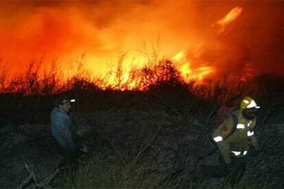 Dos bomberos haciendo frente al fuego ayer en las inmediaciones de Girona.