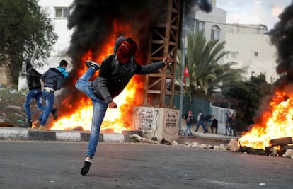 Un manifestante palestino arroja piedras contra las tropas israelíes durante los enfrentamientos en una protesta contra la decisión del presidente estadounidense Donald Trump de reconocer a Jerusalén como la capital de Israel, cerca de la ciudad Cisjordana.