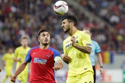 Roberto Soriano del Villarreal golpea de cabeza ante la presencia de Alin Tosca de Steaua Bucharest.