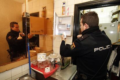 Un policía inspecciona el botiquín del bar de copas de Azca.