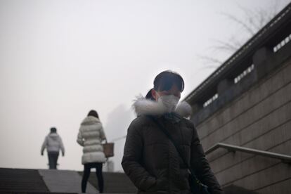 Una mujer con mascarilla camina a través de un paso inferior. Los residentes de Beijing se despertaron el día de Navidad con el cielo oscurecido por una espesa niebla tóxica.