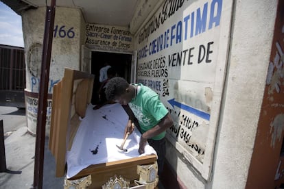 Jean Pierre Mercelien tapiza el interior de un ataúd en una tienda en el centro de Puerto Príncipe, Haití. "Es una buena vida porque nunca dejaremos de tener nuevos clientes", comentó en un patio donde varios hombres construyen ataúdes de madera y los decoran con cojines y tiradores de aluminio.