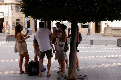 Un grupo de turistas beben agua junto a un árbol en Ronda (España), este martes.