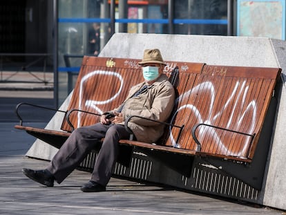 Un hombre con mascarilla sentado en un banco en Madrid.
