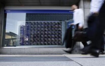 Cl&aacute;sica imagen de Tokio, con peatones pasando por delante de monitores de cotizaci&oacute;n. 