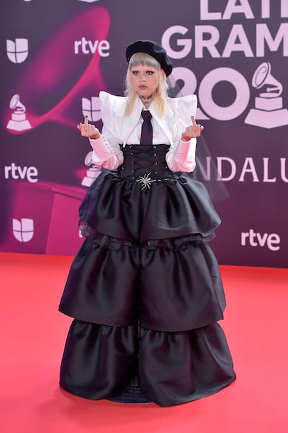 La cantante mexicana Amalia Ramrez, ms conocida como Bruses, fue una de las primeras en llegar a la alfombra roja con un curioso conjunto de dos piezas falda con volumen, cors y camisa con corbata que ha complementado con boina y velo de tul negro.