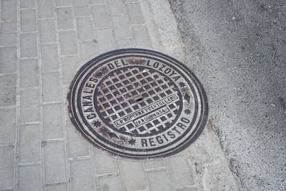 Una alcantarilla con la inscripción "Canales del Lozoya" en una calle de la colonia.