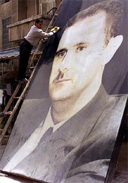Un empleado saca brillo a un cartel del presidente El Asad, ayer en Damasco.