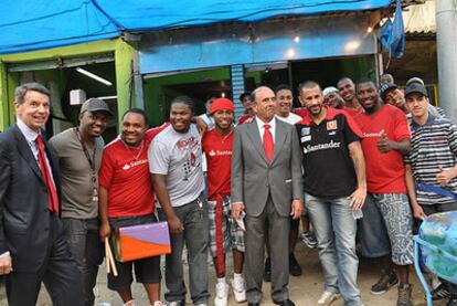 El presidente del Grupo Santander, Emilio Botín (en el centro), y el presidente de Santander Brasil, Marcial Portela, con vecinos de la favela Alemão.