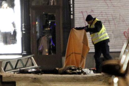 Un policía tapa el cadáver del fallecido tras un doble ataque en una zona comercial de Estocolmo, en el que también han resultado heridas otras dos personas.