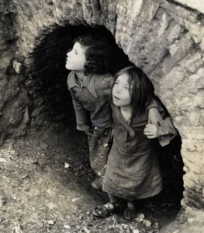 Niños refugiados bajo un arco de mampostería en la Guerra Civil.