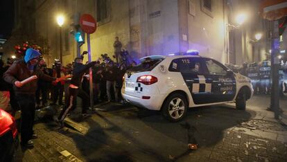 Varios manifestantes, con las caras tapadas, junto al coche de la Policía Municipal atacado el 14 de diciembre de 2013 en el centro de Madrid.