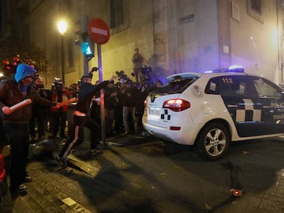 Varios manifestantes, con las caras tapadas, junto al coche de la Policía Municipal atacado el 14 de diciembre de 2013 en el centro de Madrid.