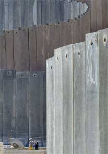 Una mujer palestina tiende la ropa en la azotea de su casa frente al muro.