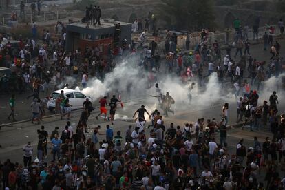 Por cuarta jornada consecutiva, Beirut se despertó con el ruido de los vidrios rotos recogidos en las calles por los habitantes y un ejército de voluntarios, con escobas, movilizados desde muy temprano. En la imagen, los manifestantes corren para protegerse del gas lacrimógeno lanzado por las fuerzas de seguridad.