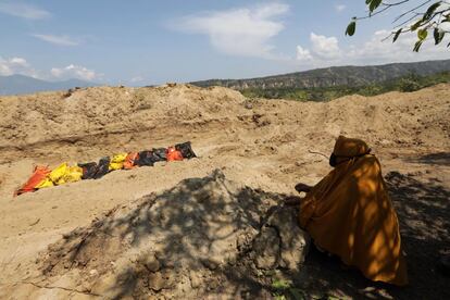 Una superviviente descansa durante un entierro masivo en un campo de Palu (Indonesia). 