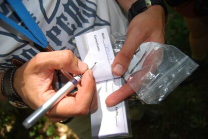 Una aficionada al 'geocahing' firma en el libro de visitas de un tesoro.