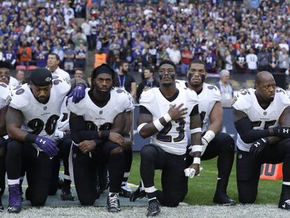 Jogadores dos Ravens se ajoelham durante a execução do hino neste domingo.