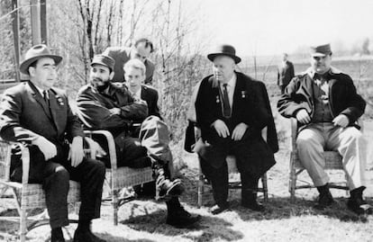 Fidel Castro conversa con Leonidas Breznev (i) y Nikita Khrushchev, a su derecha, sentados en el exterior de la residencia del líder soviético Khrushchev, que invitó al líder cubano a degustar una comida casera y descansar en la víspera del Primero de Mayo de 1963.