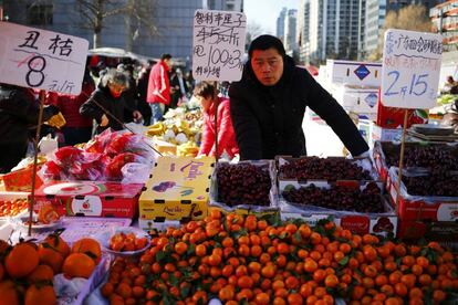 Un vendedo de fruta espera en un mercado local de Pekín (China
