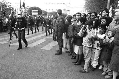 Un grupo de personas asiste en la plaza de Oriente a la retreta militar conmemorativa de la fiesta de la Comunidad de Madrid.