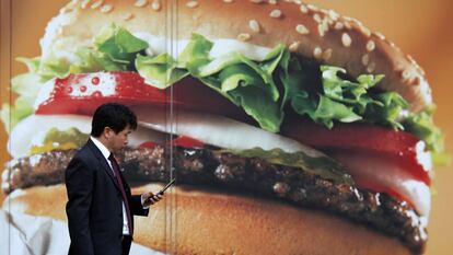 Un hombre camina junto a un anuncio de un restaurante de comida rápida, en Tokio, en una imagen de archivo.
