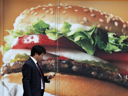 Un hombre camina junto a un anuncio de un restaurante de comida rápida, en Tokio, en una imagen de archivo.