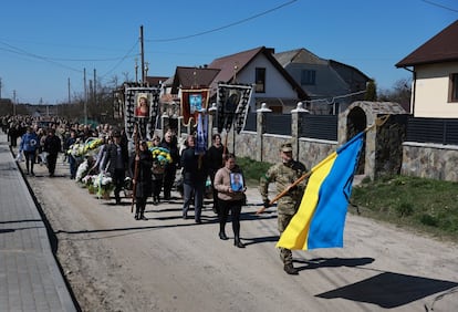 Un soldado ucranio que porta una bandera oficial del país encabeza una comitiva que se dirige al cementerio de la localidad de Starychi, donde será enterrado un compañero de armas. Starychi es un pequeño pueblo al oeste de Ucrania, a escasos 20 kilómetros de la frontera con Polonia, y a otros tantos de la base militar de Yavoriv, bombardeada a mediados de marzo por el Ejército ruso.