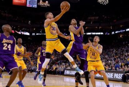 Steph Curry suspendido en el aire intenta una canasta mientras Kobe Bryant observa tenso.