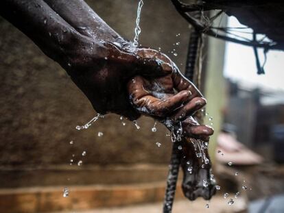 Un hombre lava sus manos en agua del grifo en un punto de recogida de agua en Kibera, en los suburbios de Nairobi (Kenia).