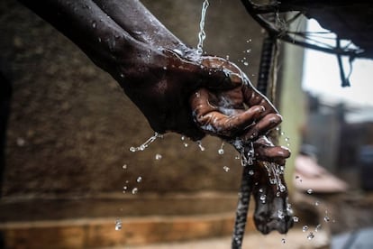 Un hombre lava sus manos en agua del grifo en un punto de recogida de agua en Kibera, en los suburbios de Nairobi (Kenia).