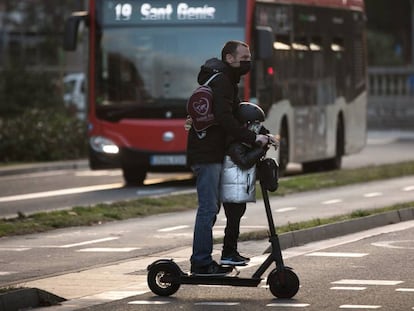 Un hombre circula con un niño en patinete, en enero.