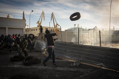 Varios trabajadores lanzan neumáticos al fuego de la barricada para reavivarlo.