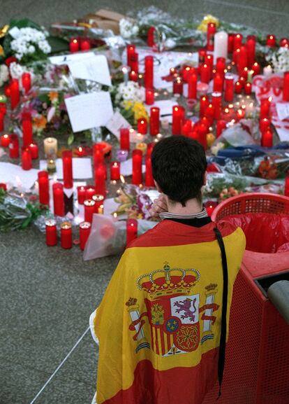 12 de marzo de 2004. Madrid. Un joven cubierto con la bandera española contempla las velas colocadas en la estación de Atocha en memoria de las víctimas del 11-M un día después de los atentados.