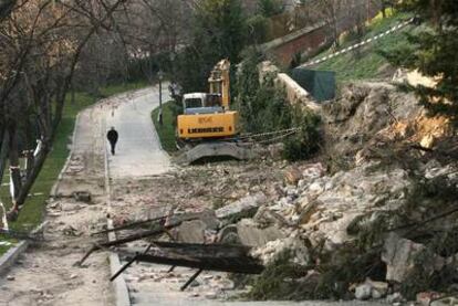 Una máquina trabaja junto a los restos del muro que se derrumbó en Las Vistillas.